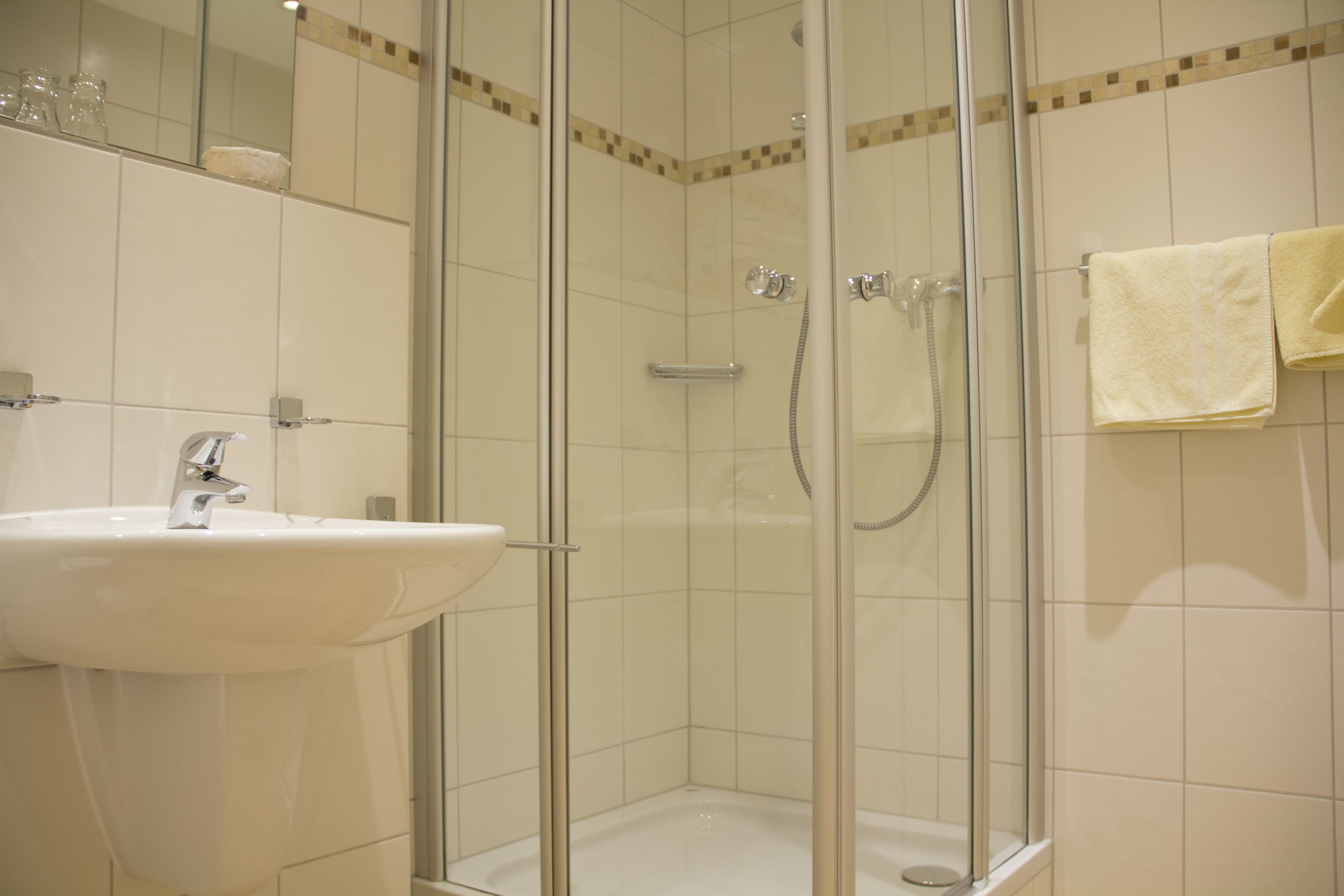 A bathroom with a glass-enclosed shower, a sink, and a towel rack.