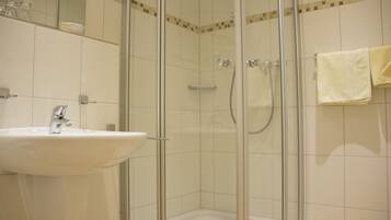 A bathroom with a glass-enclosed shower, a sink, and a towel rack.