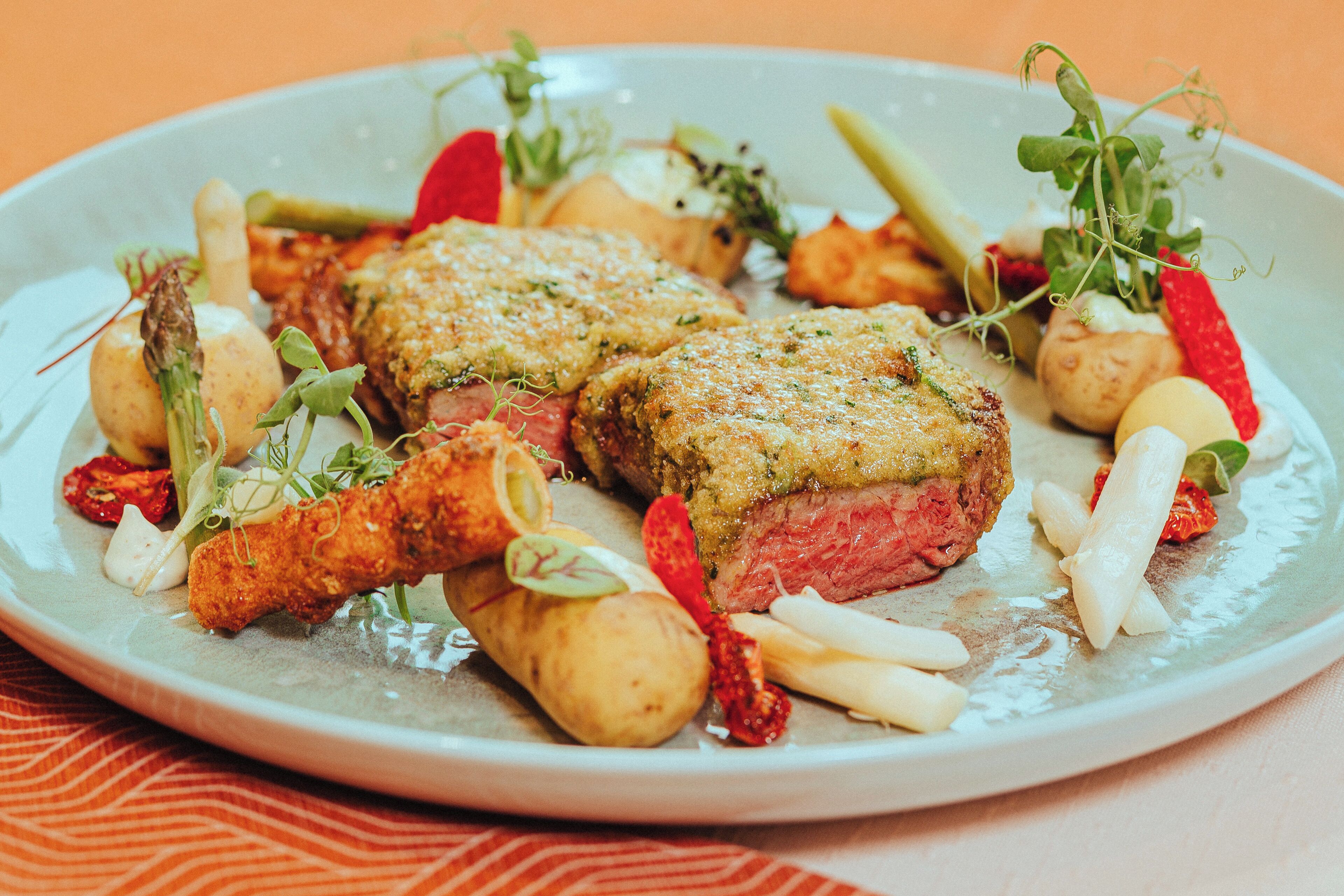 Un plato de comida con dos porciones de carne empanizada, papas y diversas verduras.