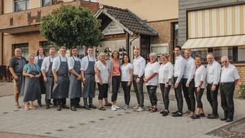 A group of people standing in front of a building with a sign that reads "Hotel Restaurant Zur Neuburg."