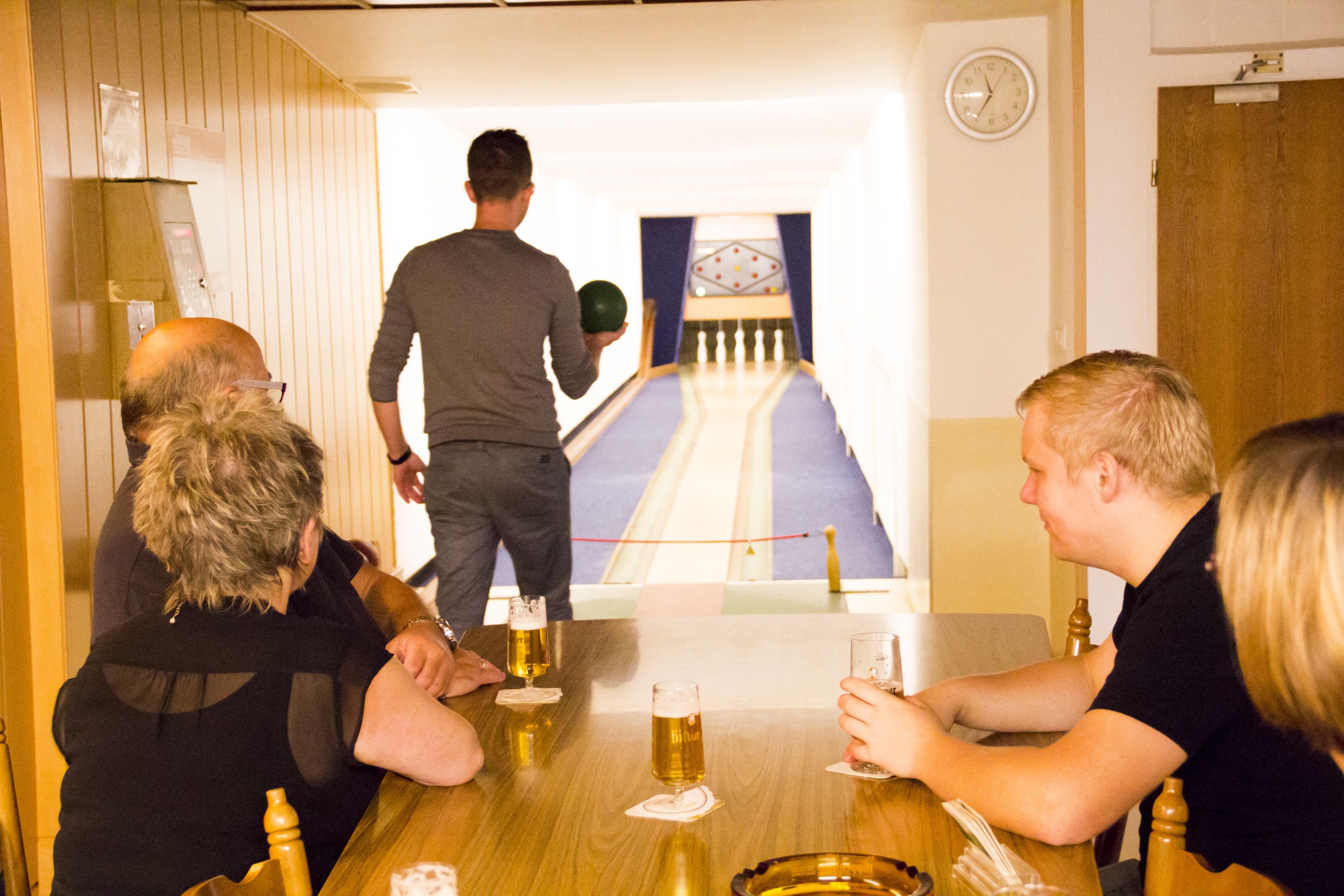 A group of people seated around a wooden table with beer glasses, engaged in conversation.