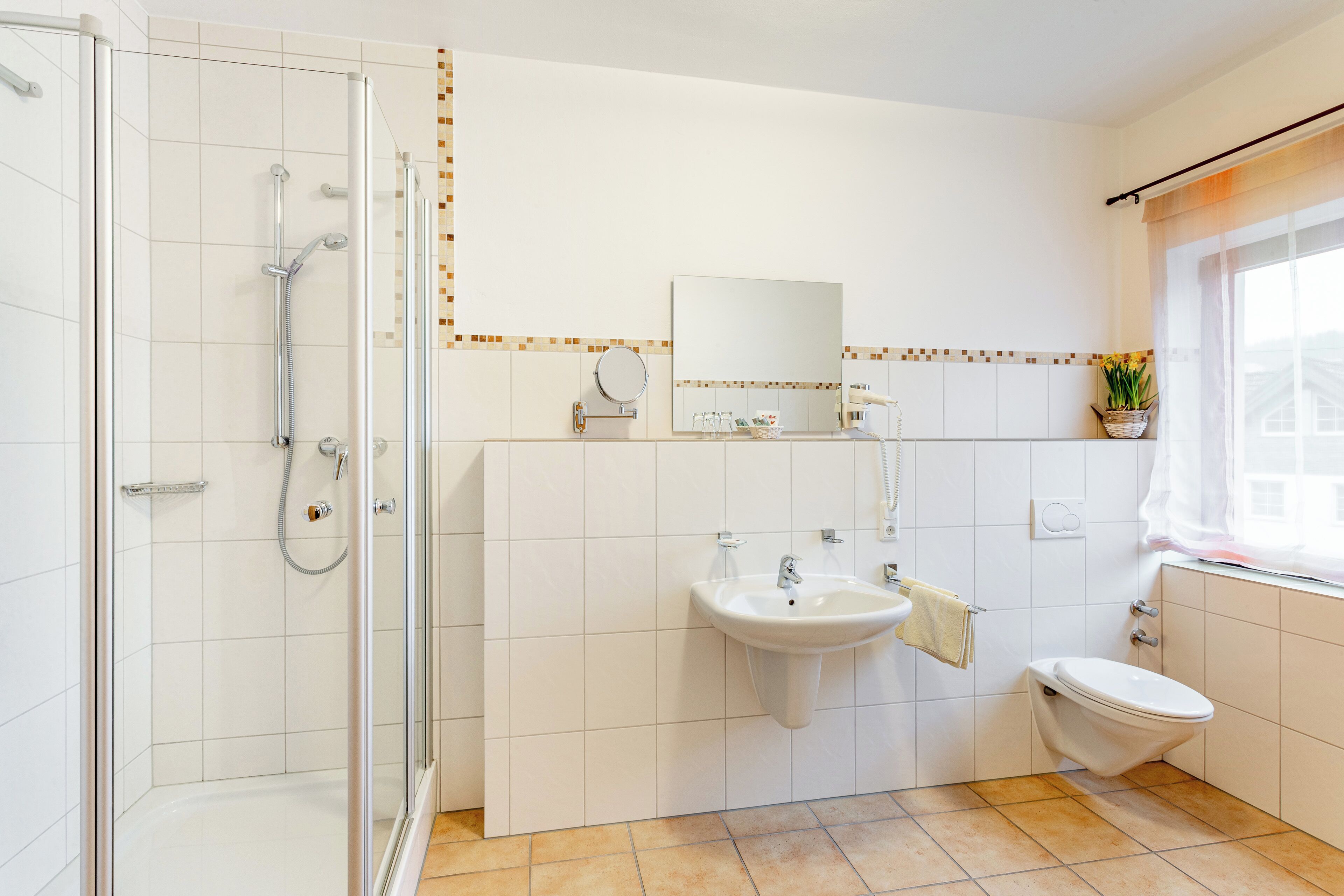 Een moderne badkamer met een douche met glazen wand, een wastafel, toilet en een spiegel.