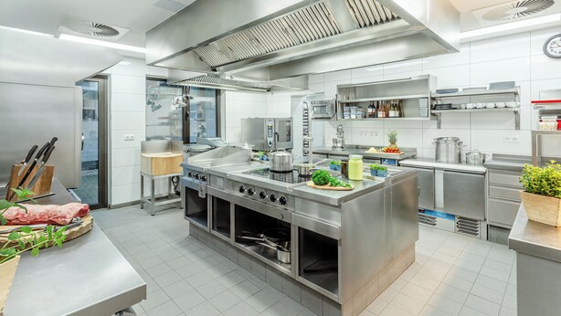 A modern kitchen with stainless steel appliances, a large island, and a clock on the wall. - Zur Neroburg (Neroth)