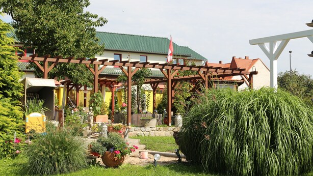 A garden with a pergola, potted plants, and a flag. - Haus Elbromantik (Sandau)