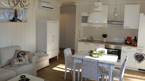 A modern kitchen with white cabinets, a dining table with chairs, and a chandelier. - Haus Elbromantik (Sandau)