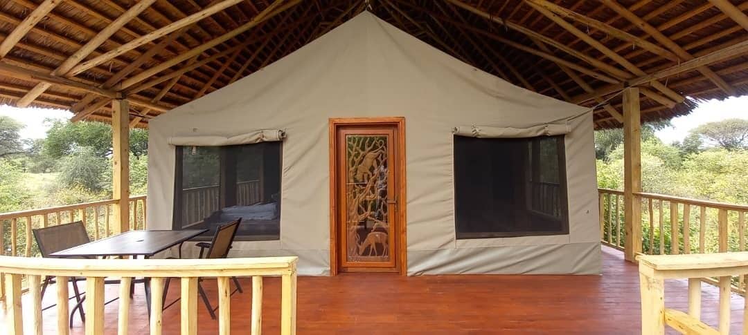 Een tent met een houten terras, een tafel en stoelen.