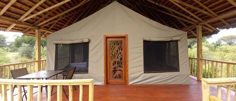 Een tent met een houten terras, een tafel en stoelen.