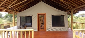 Una carpa con una terraza de madera, una mesa y sillas.