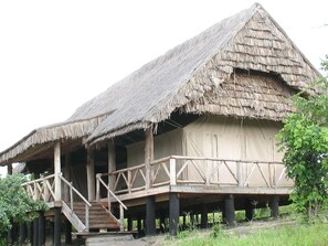 Una estructura tradicional con techo de paja, balcón de madera y escalera.