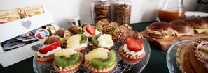 Variedad de postres, incluyendo cupcakes con frutas, pasteles y sándwiches sobre una mesa.