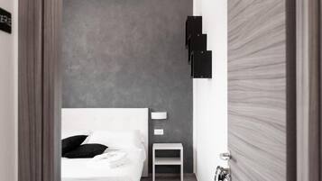A modern hotel room with a bed, bedside table, and a chair.