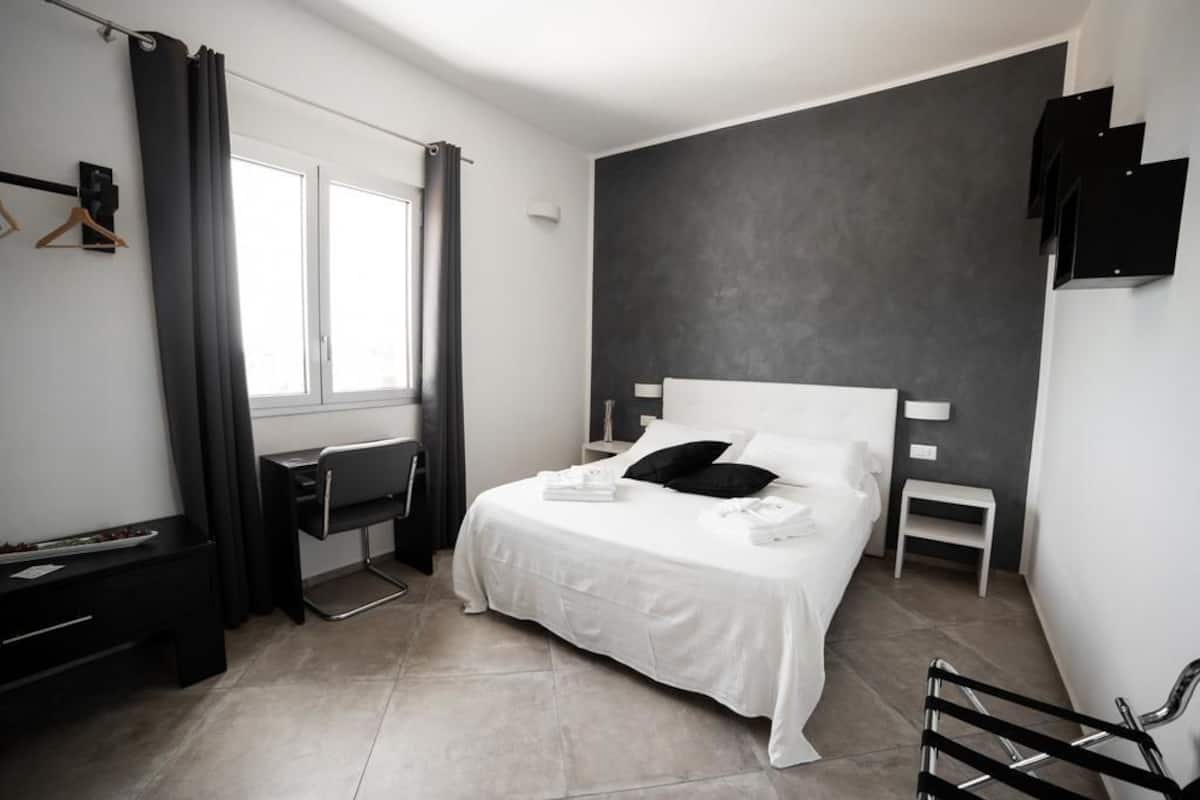 A modern bedroom with a large bed, a desk, and a chair.