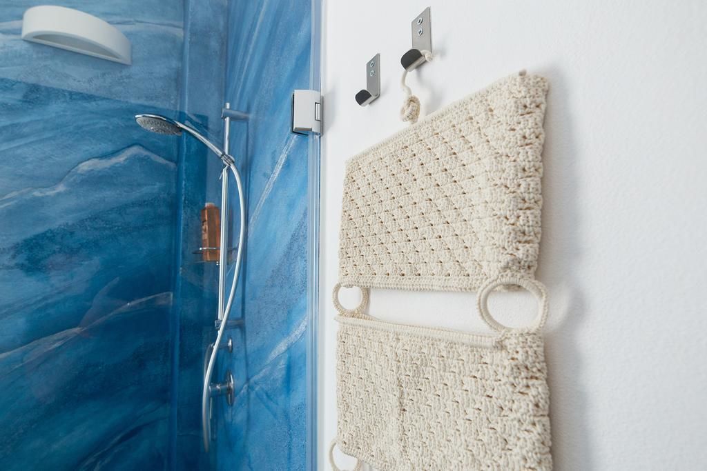 A bathroom with a blue marble shower enclosure, a white towel, and a white towel rack with hooks.