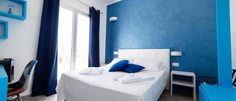 Quarto de hotel com uma cama grande, uma mesa, uma cadeira e uma pequena mesa.