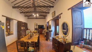 Un comedor rústico con una larga mesa de madera, sillas y un televisor al fondo.