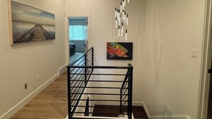 A modern interior with a wooden floor, a staircase, a painting of a pier, and a colorful artwork. - Lakefront resort, pool, tennis, pickleball with a private beach, fast EV charger (Whitefish)