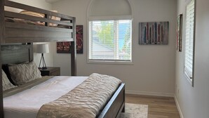 A bedroom with a bunk bed, a large window, and artwork on the walls. - Lakefront resort, pool, tennis, pickleball with a private beach, fast EV charger (Whitefish)