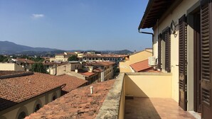 A view of a residential area with terracotta-tiled roofs, a balcony with a tiled floor, and a clear sky. - Fortezza Fourth Floor - 6 pax (Florence)