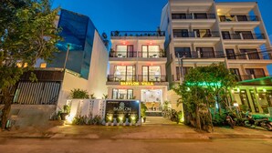 A multi-story hotel with balconies, a signboard, and potted plants. - Babylon Hoi An Central Villa (Da Nang)