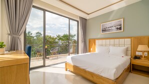 A modern hotel room with a large bed, a wooden nightstand, a desk, and a balcony with a chair. - Babylon Hoi An Central Villa (Da Nang)
