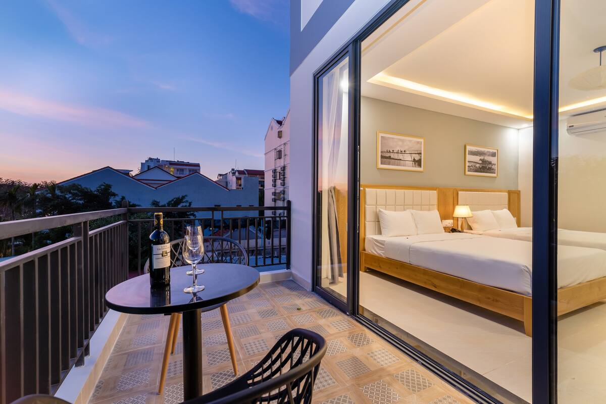 A balcony with a table, two wine glasses, and a bottle of wine.