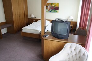 A hotel room with a bed, a television on a wooden table, a chair, and a painting on the wall. - Hotel Niederée (Bad Breisig)