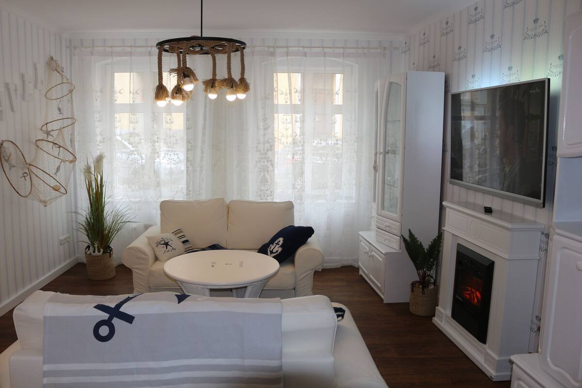 A living room with a fireplace, a television, and a sofa with decorative pillows.