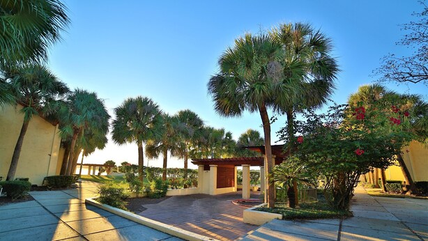 A paved courtyard with palm trees and a pergola structure. - Cozy One Bedroom Lakefront Villa Close to the Attractions (Orlando)