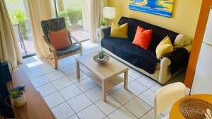 A living room with a sofa, armchair, coffee table, and a painting on the wall. - Cozy One Bedroom Lakefront Villa Close to the Attractions (Orlando)