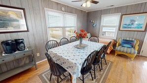 A dining area with a table set for six, surrounded by chairs, a coffee station, and a wicker chair. - Ocean Front at the Washout~ Foose's Folly (Folly Beach)