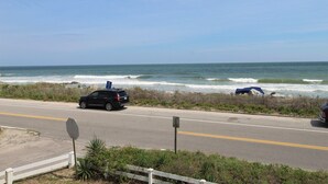 A coastal road with a black SUV, a stop sign, and a wooden fence. - Ocean Front at the Washout~ Foose's Folly (Folly Beach)