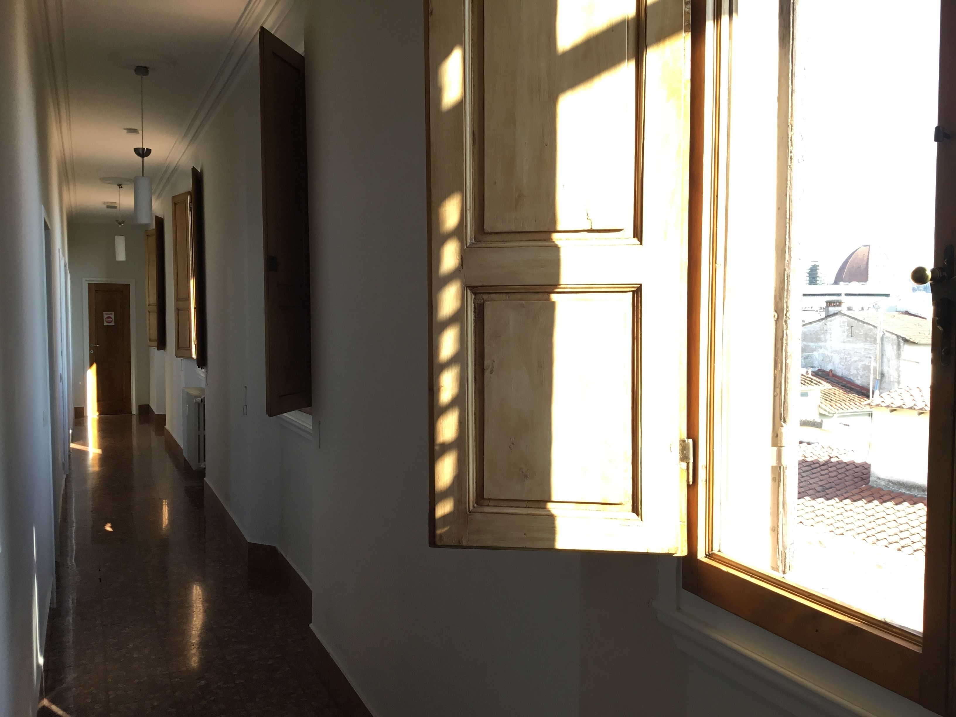 A hallway with a large window, a door, and a radiator.