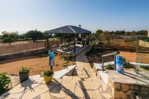 A covered outdoor seating area with stone flooring and potted plants. - Alonaki Apartments (Zakynthos)