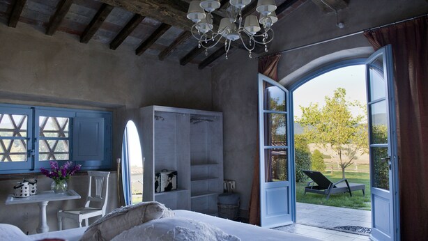 Une chambre à coucher avec un grand lit, une commode, une chaise et une fenêtre donnant sur l’extérieur.