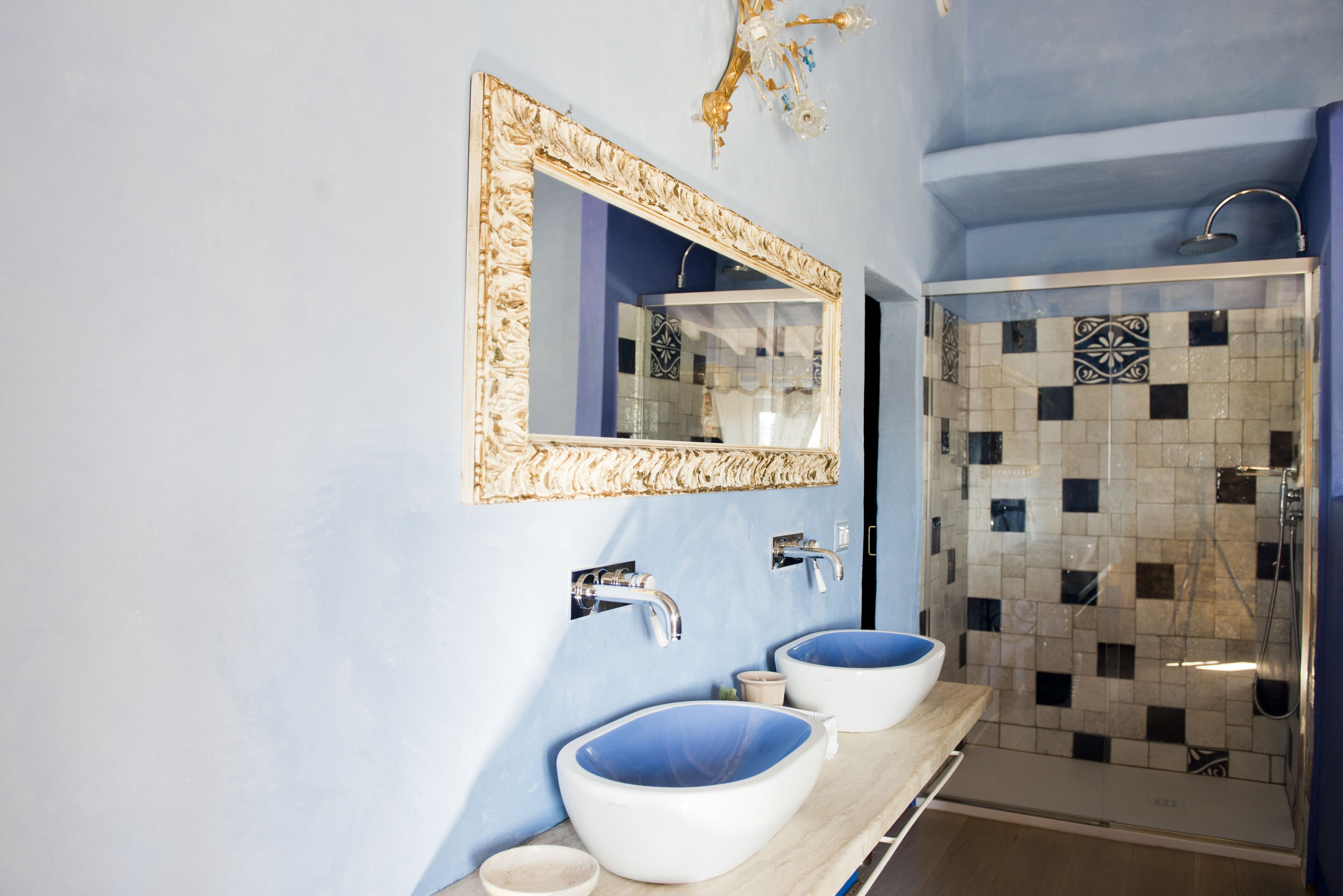 A bathroom with two sinks, a shower, and a decorative mirror.