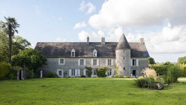 A large stone building with a tower, surrounded by a grassy field and trees. - Chateau Le Colombier - Chambres d'hôtes (Carentan les Marais)