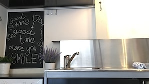 Una cocina con un lavamanos de acero inoxidable, una pizarra con un mensaje positivo y una planta en maceta.