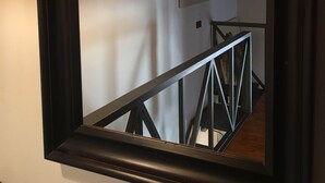 A mirror reflecting a staircase with a black metal railing and three hanging pendant lights.