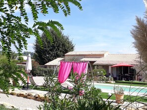 A poolside area with a tiled roof, a pool, and a patio with a table and chairs. - La Colombe (Tourrettes)