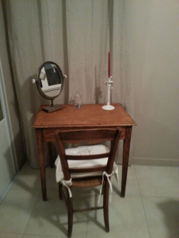 Una mesa de madera con una silla, un espejo y un candelabro.