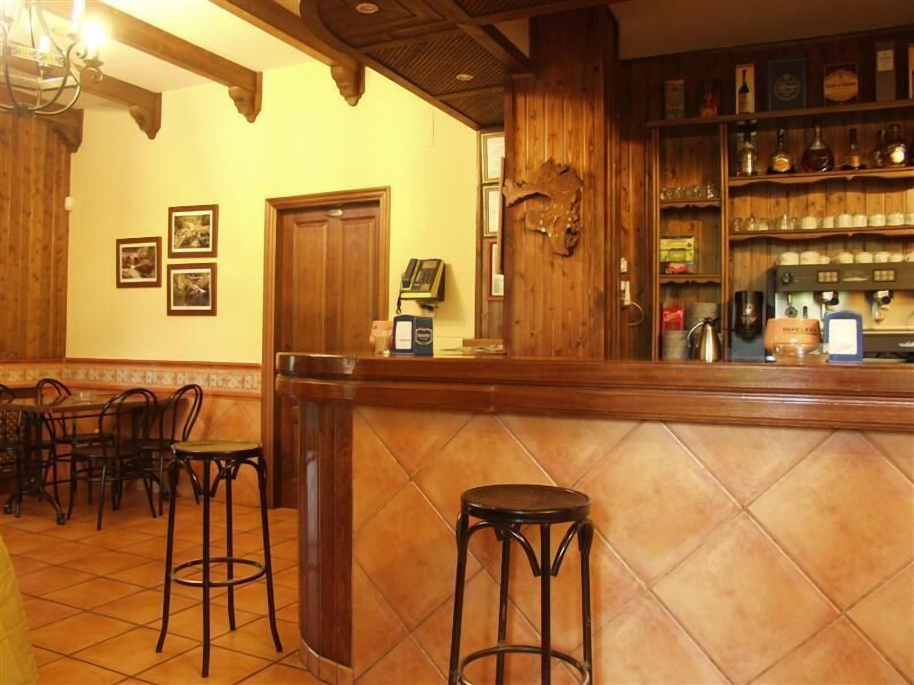 Zona de bar con decoración de madera, una barra y taburetes.