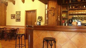 Zona de bar con decoración de madera, una barra y taburetes.