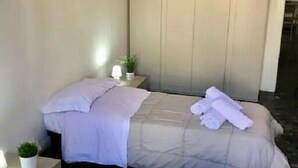 Una habitación de hotel con dos camas, una mesita de noche con lámpara y una planta pequeña en maceta.