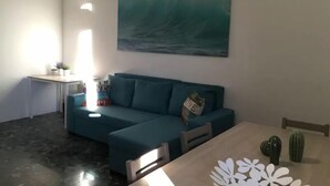 Una sala de estar con un sofá color turquesa, una mesa de centro y un cuadro de una ola.