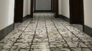 Un pasillo con piso estampado, puertas de madera y una lámpara central.