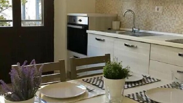 Una cocina moderna con armarios blancos, horno empotrado y ventana con vistas a la ciudad.