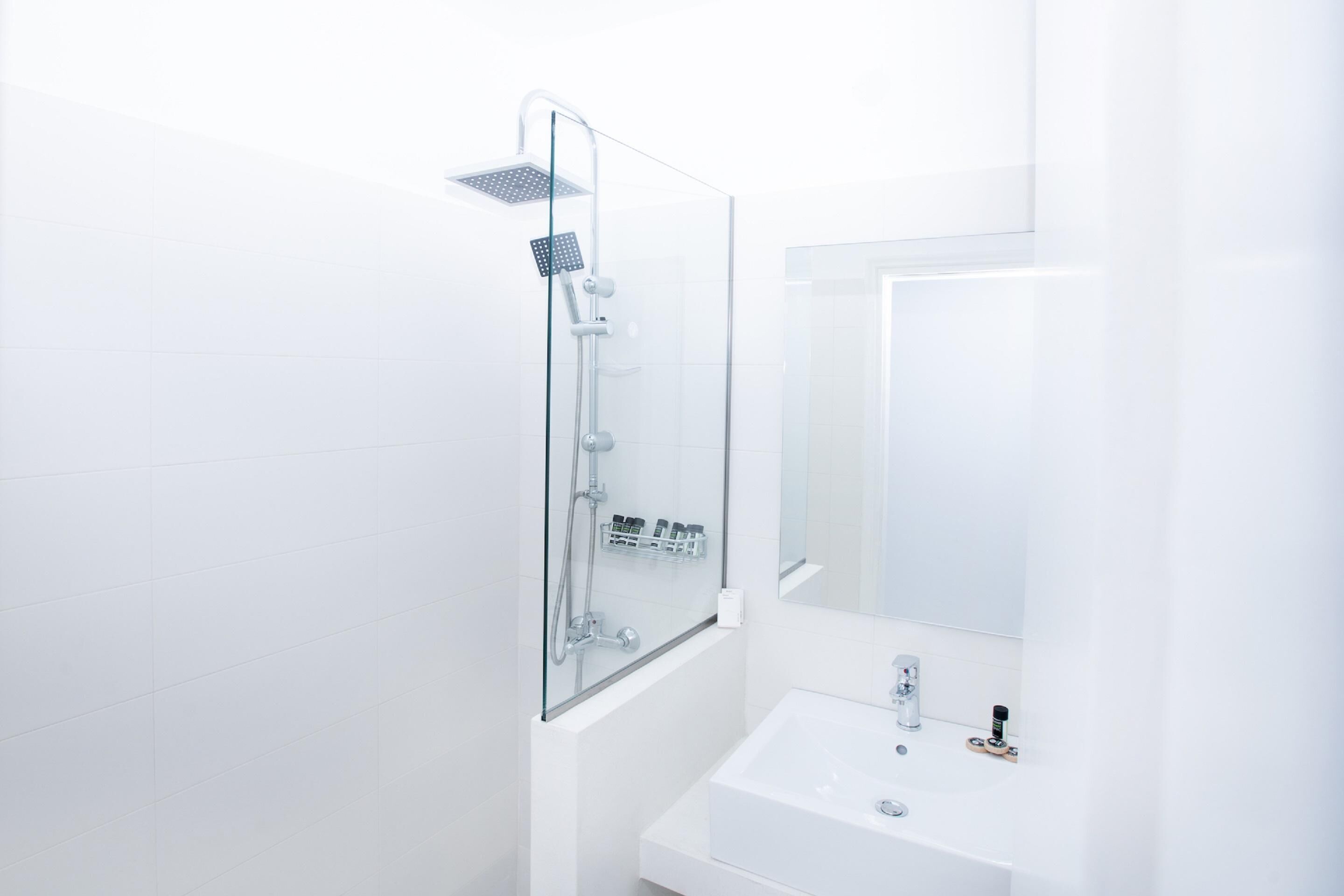 A modern bathroom with a glass-enclosed shower, a white sink, and a mirror.