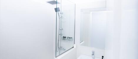 A modern bathroom with a glass-enclosed shower, a white sink, and a mirror.