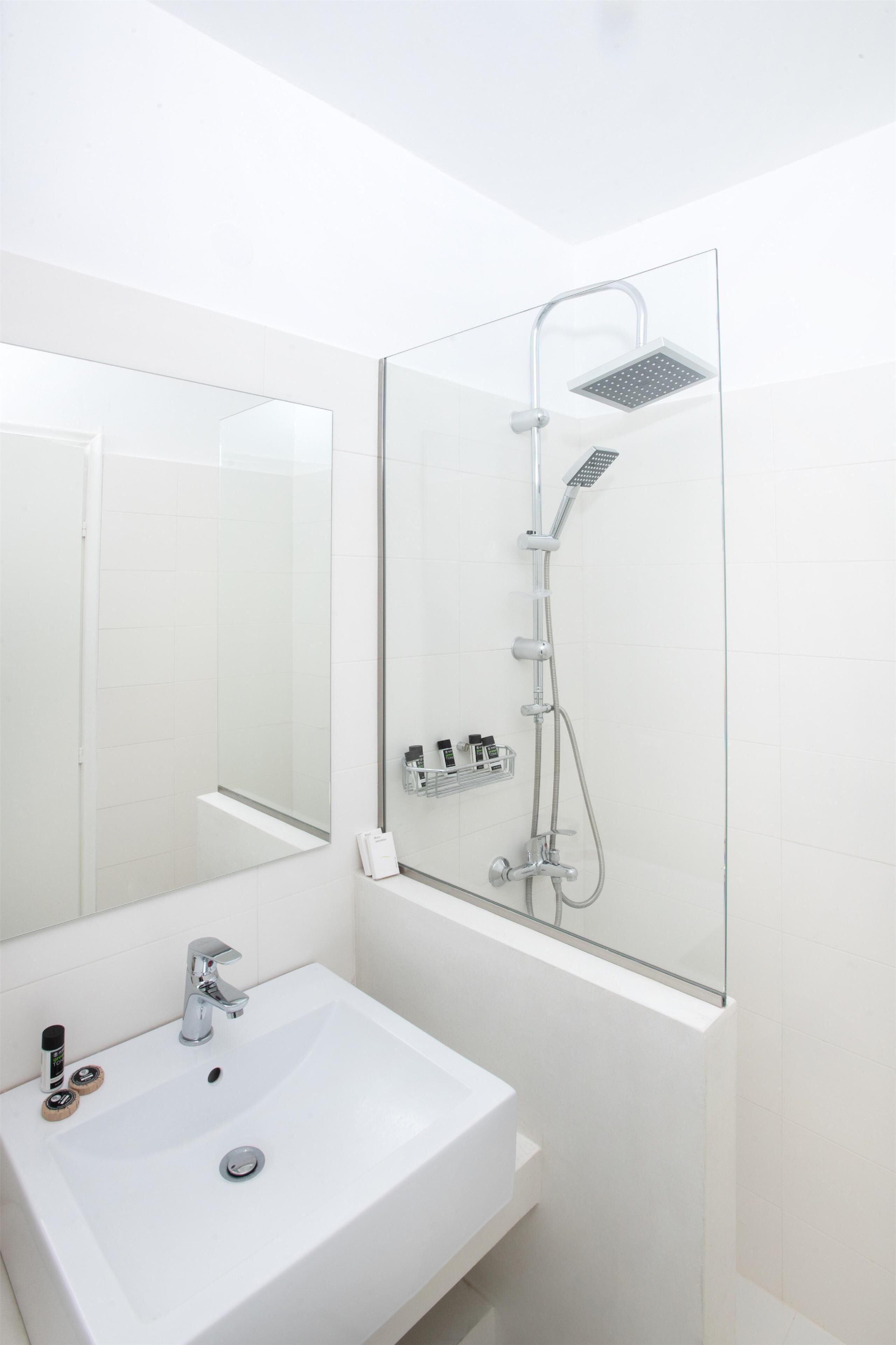 A modern bathroom with a white sink, a mirror, and a glass-enclosed shower with a handheld showerhead.