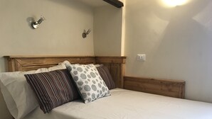 A bed with a wooden headboard, white bedding, and patterned pillows. - Vecchia Volta (Florence)
